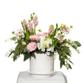 Trendy arrangement of pink gerberas, hyacinth and mixed blooms in a white fluted pot