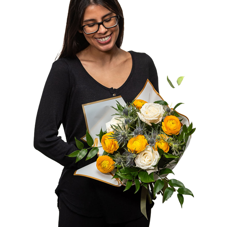Sunkissed bouquet of yellow and orange roses with eucalyptus, held by a florist
