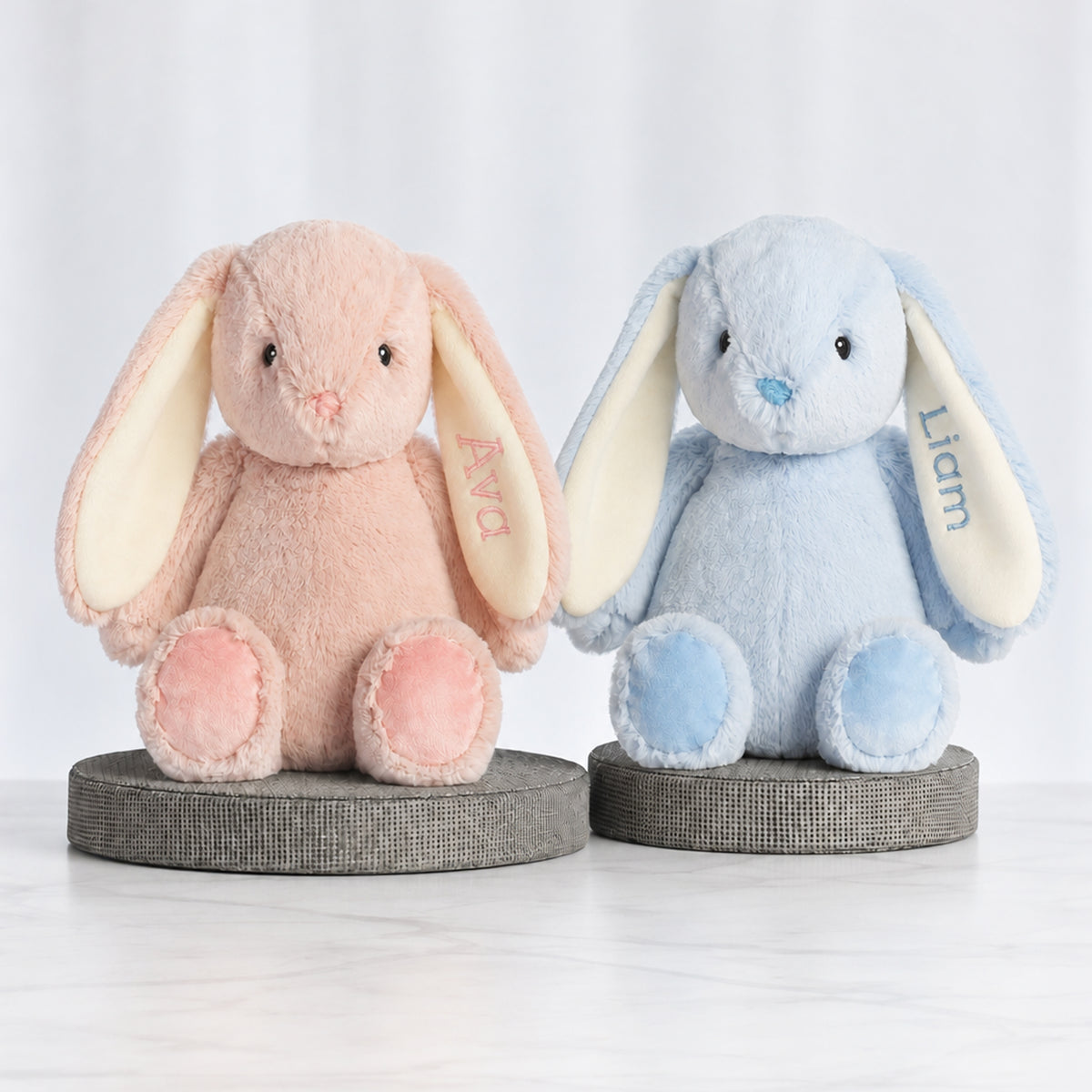 Two personalised plush bunnies, one pink and one blue, each embroidered with a name