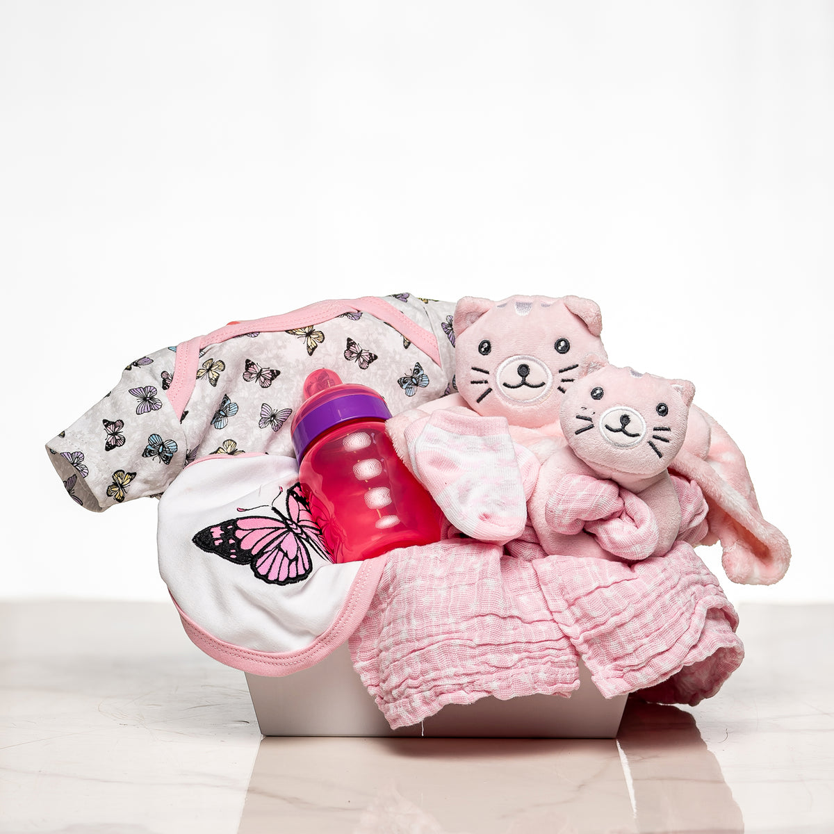 Everyday Essentials baby girl gift with pink sleepsuits, a bib, a bottle and a blanket