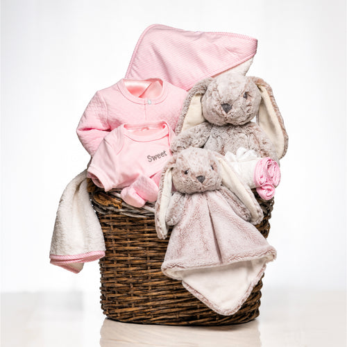 Hoppy Hamper baby girl gift in a woven basket with a pink blanket, a plush bunny and a comforter