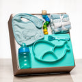 Mealtime Must Haves baby boy gift box with a teal bib, a divided plate, a spoon, a bottle and cloths