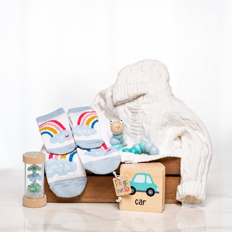 Classic Comforts baby boy gift with a cream knitted set, rainbow socks, a rattle and a wooden car