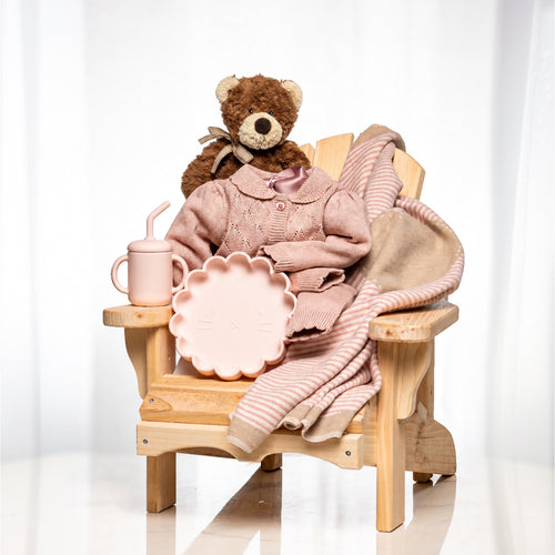 Muskoka Bear baby girl gift, a wooden chair with a teddy, a pink knitted blanket and a sippy cup