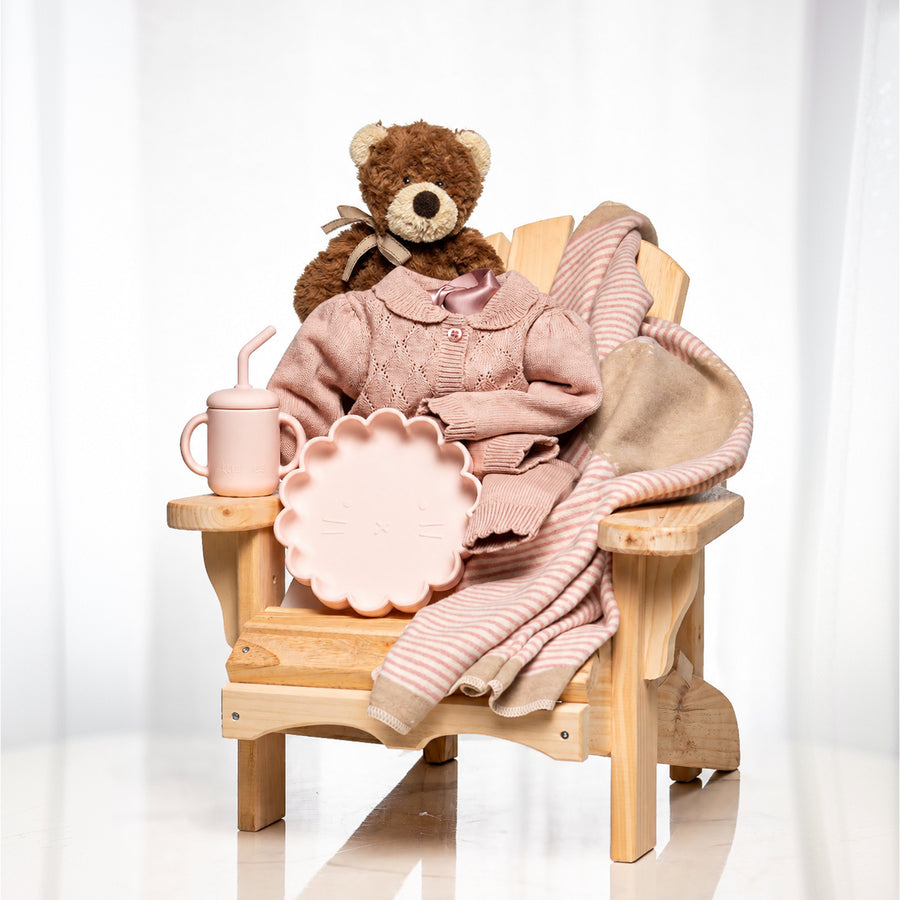 Muskoka Bear baby girl gift, a wooden chair with a teddy, a pink knitted blanket and a sippy cup