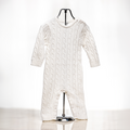 Cream cable knit baby onesie displayed on a stand