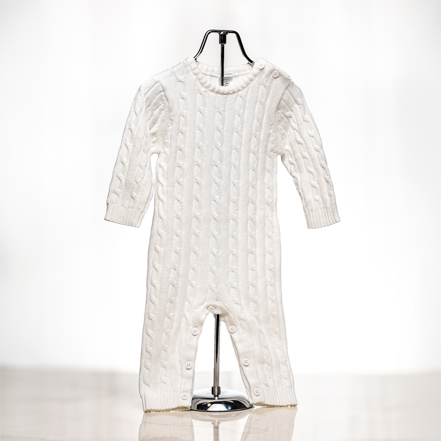 Cream cable knit baby onesie displayed on a stand
