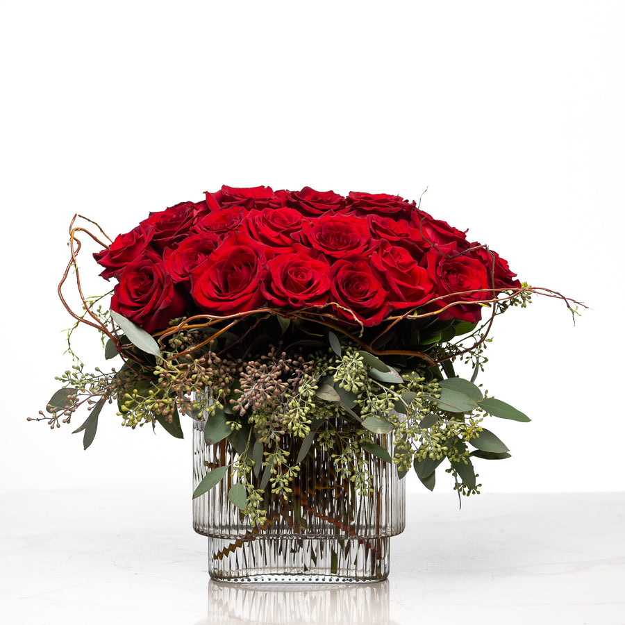 Always Yours arrangement of red roses massed in a clear glass vase with eucalyptus