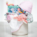 Bath Time baby girl gift set in a woven basket with a hooded towel, foam puzzle and pink plush toy