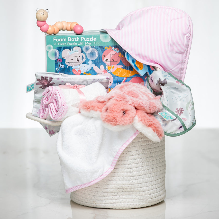 Bath Time baby girl gift set in a woven basket with a hooded towel, foam puzzle and pink plush toy