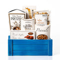 Bites of Bliss gift crate: a blue slotted wood crate with butter pretzels, sea salt caramel roca, French truffles, honey roasted peanuts and cookies and cream caramel popcorn