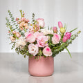 Blushing Beauty arrangement of blush roses, tulips and eucalyptus in a pink ribbed vase