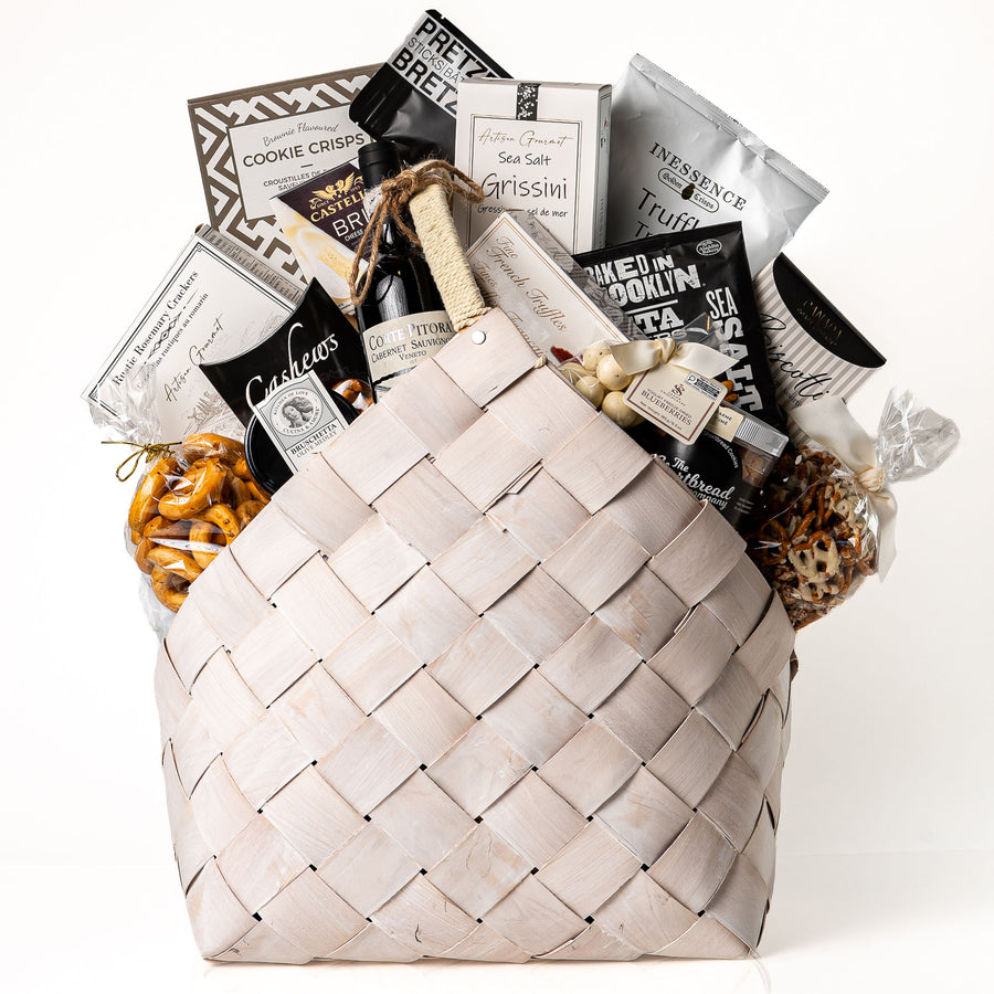 Bountiful Bundle Large: a white washed woven carrier with a bottle of red wine, Castello brie, grissini, crackers, cookie crisps, biscotti and gourmet snacks