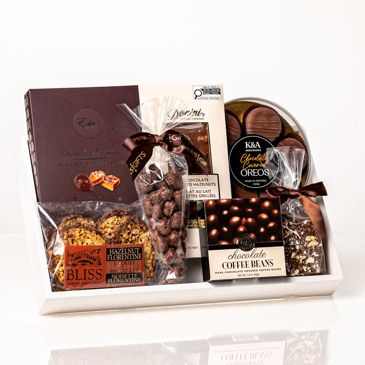 Cocoa gift: a white wood base filled with Bliss hazelnut florentines, chocolate coffee beans, Esta truffles, chocolate covered Oreos, a Donini chocolate bar and chocolate bark