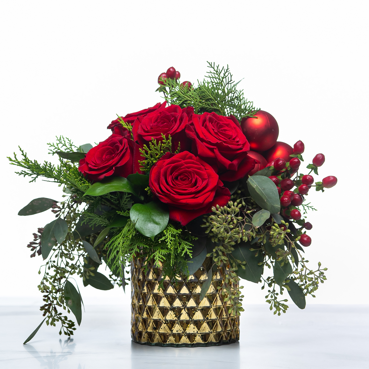 Crimson Evergreen holiday centrepiece of red roses, baubles and berries in a gold textured pot