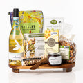 Crisp gift: an acacia wood footed serving board with a bottle of Fonteamonte Trebbiano, Stellar pretzel braids, a baked dip trio, Partners crackers, a Venchi bar, bruschetta and pistachios