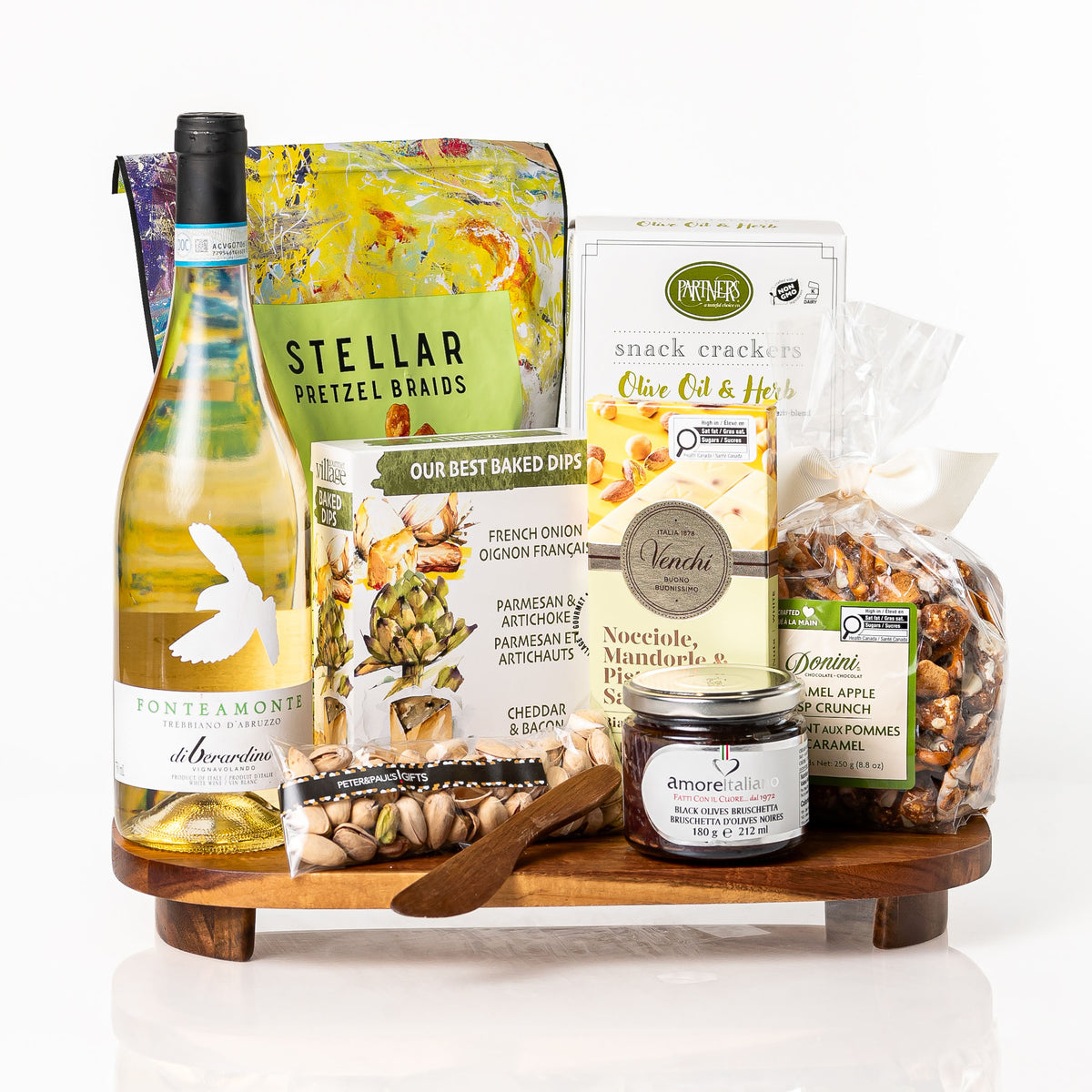 Crisp gift: an acacia wood footed serving board with a bottle of Fonteamonte Trebbiano, Stellar pretzel braids, a baked dip trio, Partners crackers, a Venchi bar, bruschetta and pistachios