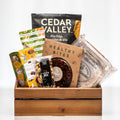 Curated Comforts wooden crate with Cedar Valley pita chips, healthy bites, nuts and cookies