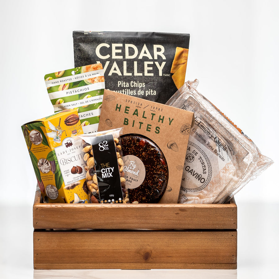 Curated Comforts wooden crate with Cedar Valley pita chips, healthy bites, nuts and cookies