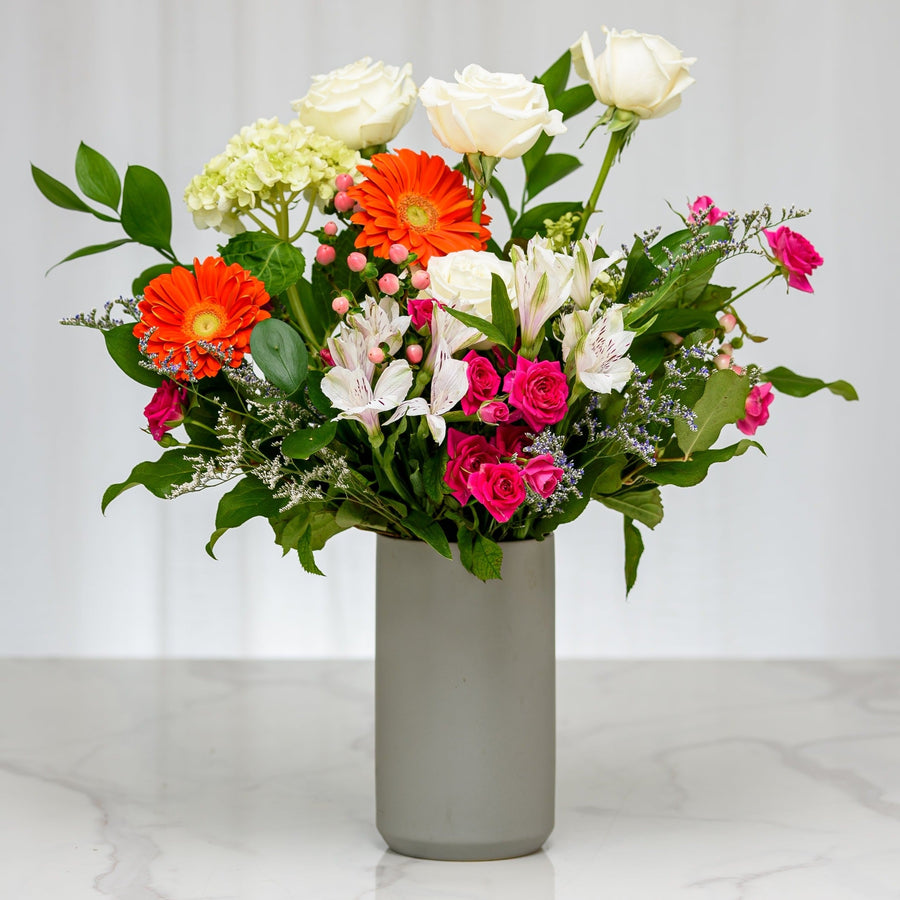 Eden bouquet of white and pink roses, orange gerberas and mixed blooms in a frosted grey vase