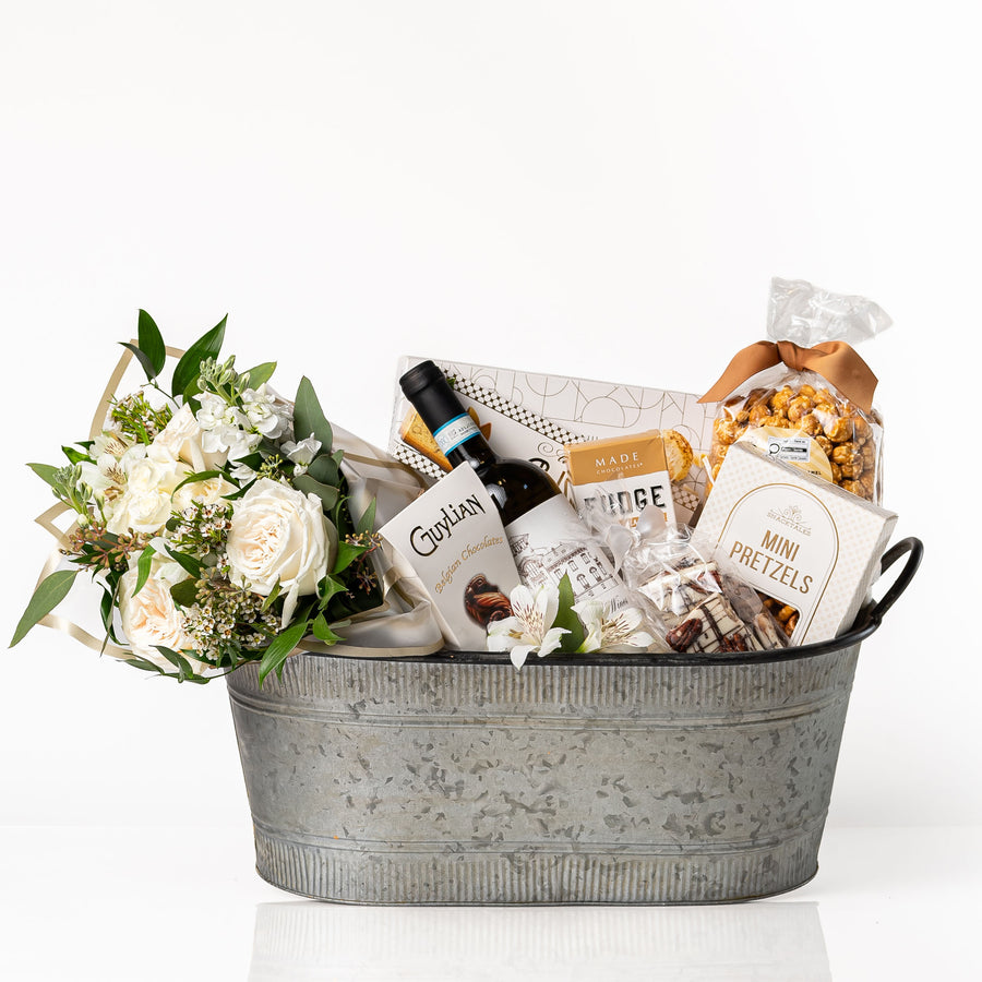 Elegance Large gift basket: a galvanised oval tub with a bouquet of ivory roses and white alstroemeria, a bottle of red wine, Guylian Belgian chocolates, fudge, mini pretzels and caramel popcorn