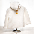 Cream knitted baby coat with a collar and wooden buttons displayed on a stand