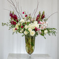 Emotions tall arrangement of red and white roses, hydrangea and blossom branches in a glass vase