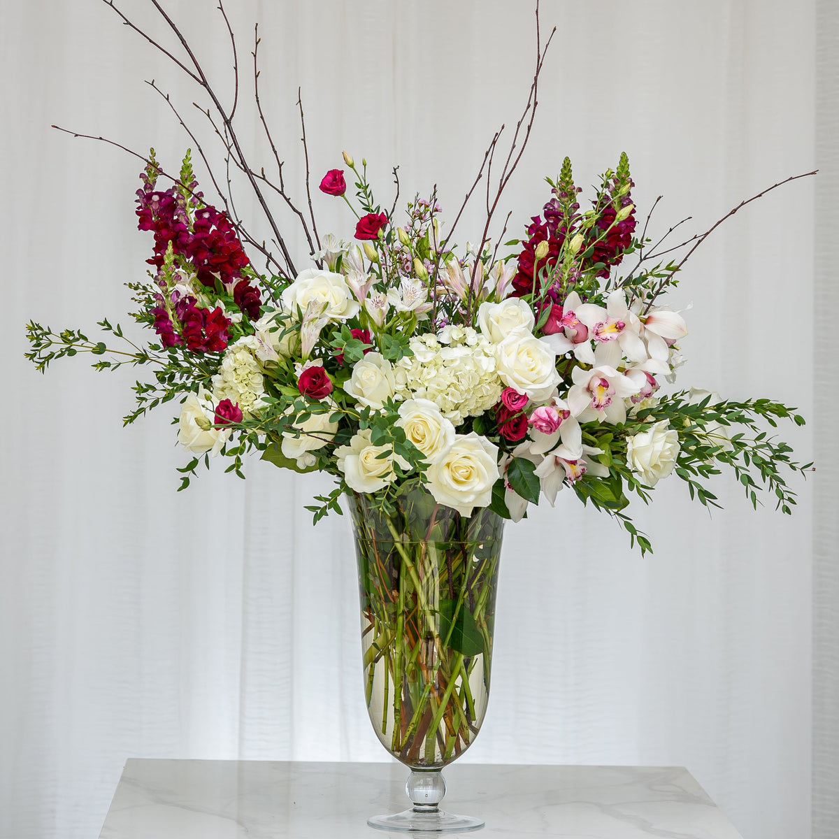 Emotions tall arrangement of red and white roses, hydrangea and blossom branches in a glass vase