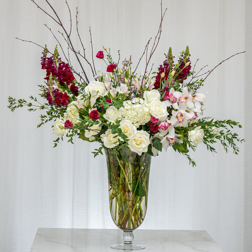 Emotions tall arrangement of red and white roses, hydrangea and blossom branches in a glass vase