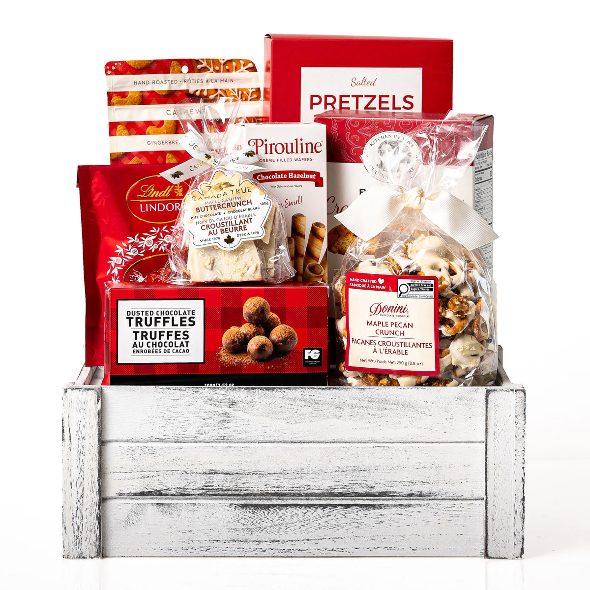 Festive Faves Medium: a white washed wood crate with Lindt Lindor truffles, Pirouline wafer rolls, salted pretzels, cranberry almond biscotti, a Donini bar and maple buttercrunch bark