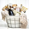 Fireside Favourites gift basket with a bottle of wine, chocolates and a cream throw blanket