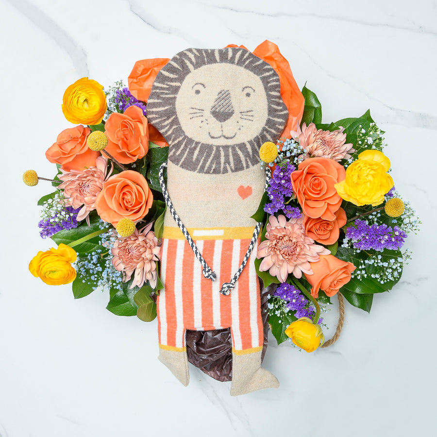 Flourishing Fussenegger lion plush toy surrounded by a wreath of orange, peach and purple blooms