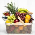Large fresh fruit basket with pineapple, grapes, apples, bananas, berries and citrus in a wire basket