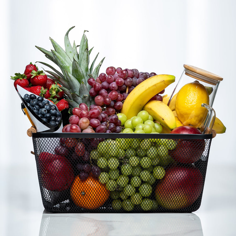 Small fresh fruit basket with pineapple, grapes, bananas, berries and citrus in a black wire basket
