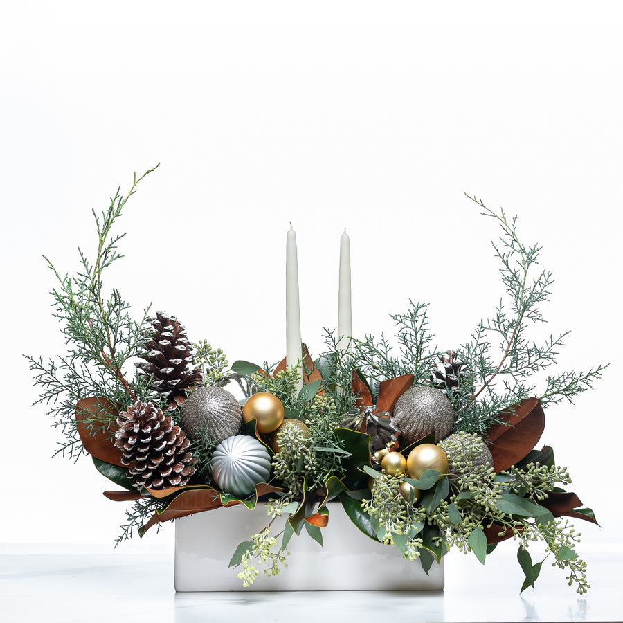 Holiday Celebration arrangement with taper candles, silver and gold baubles, pine cones and evergreen