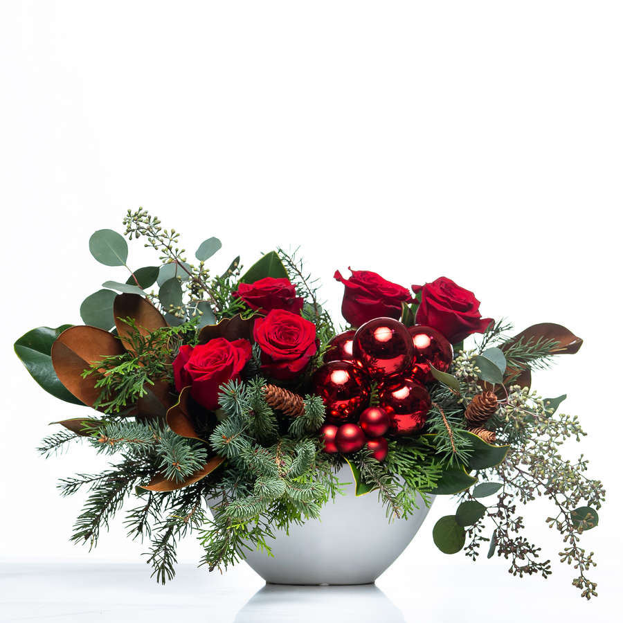 Holiday Splendor arrangement of red roses, magnolia leaves, berries and eucalyptus in a white bowl