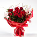 Kiss Me bouquet of red roses with curled willow, wrapped in pink and tied with a red ribbon