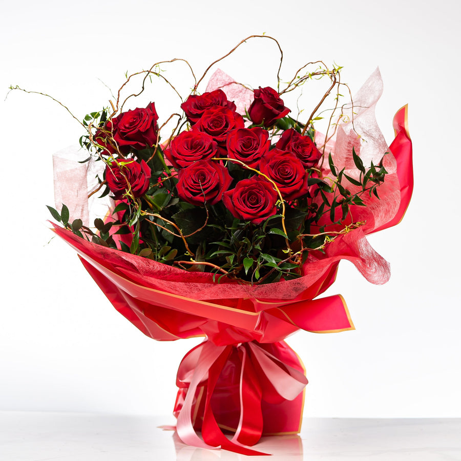 Kiss Me bouquet of red roses with curled willow, wrapped in pink and tied with a red ribbon