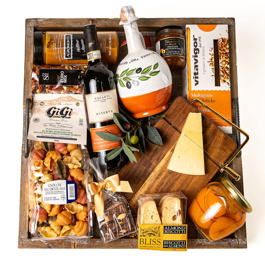 Mediterranean Moments: a square rustic wooden tray with a bottle of Sensi Chianti Riserva, extra virgin olive oil, Gigi veggie gnocchi, Parmigiano on an acacia cheese slicing board, peach halves and biscotti