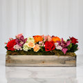 Moonstruck floral arrangement of red roses, orange ranunculus and orchids in a rustic wooden box