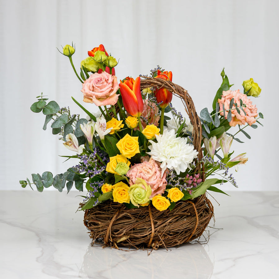 Nesting Peeps spring arrangement of tulips, roses and daisies in a woven twig nest basket