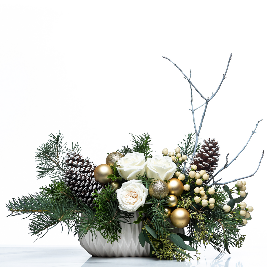 Noel Forest arrangement of white roses, gold baubles, pine cones and evergreen in a white pot