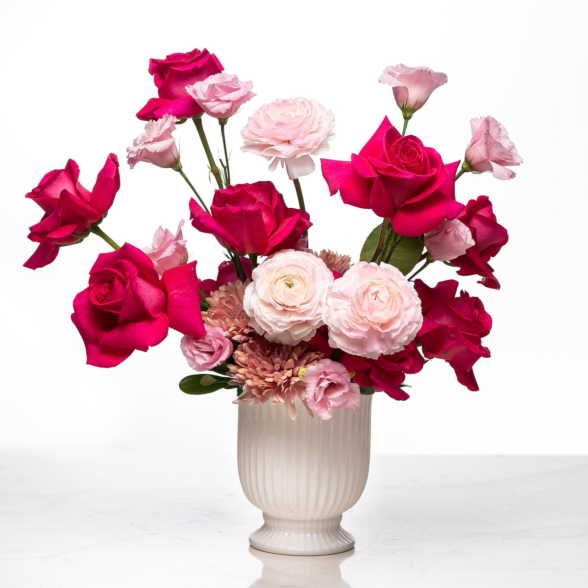 P.S. I Love You arrangement of pink and magenta roses with ranunculus in a white fluted vase