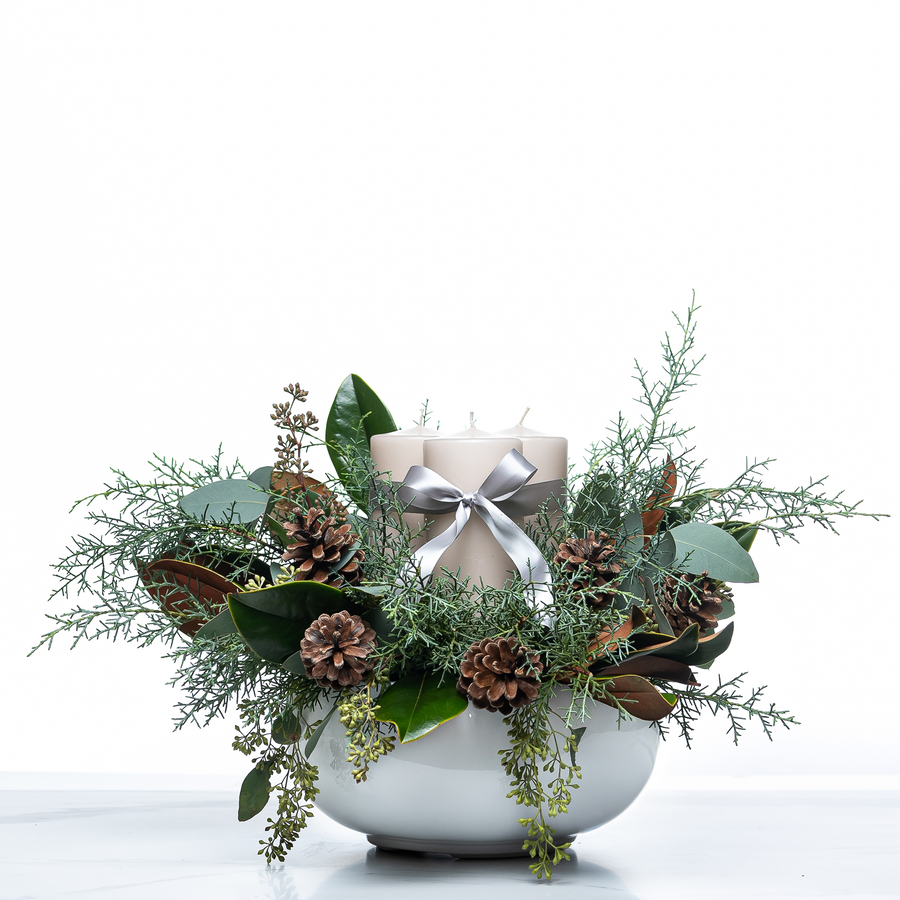 Pillar and Pine holiday centrepiece with a silver ribboned pillar candle, pine cones and magnolia