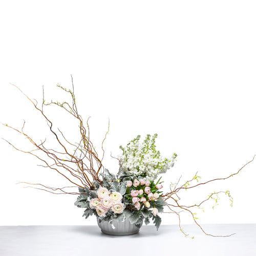 Poised Beauty arrangement of cream blooms with bare branches and eucalyptus in a grey bowl