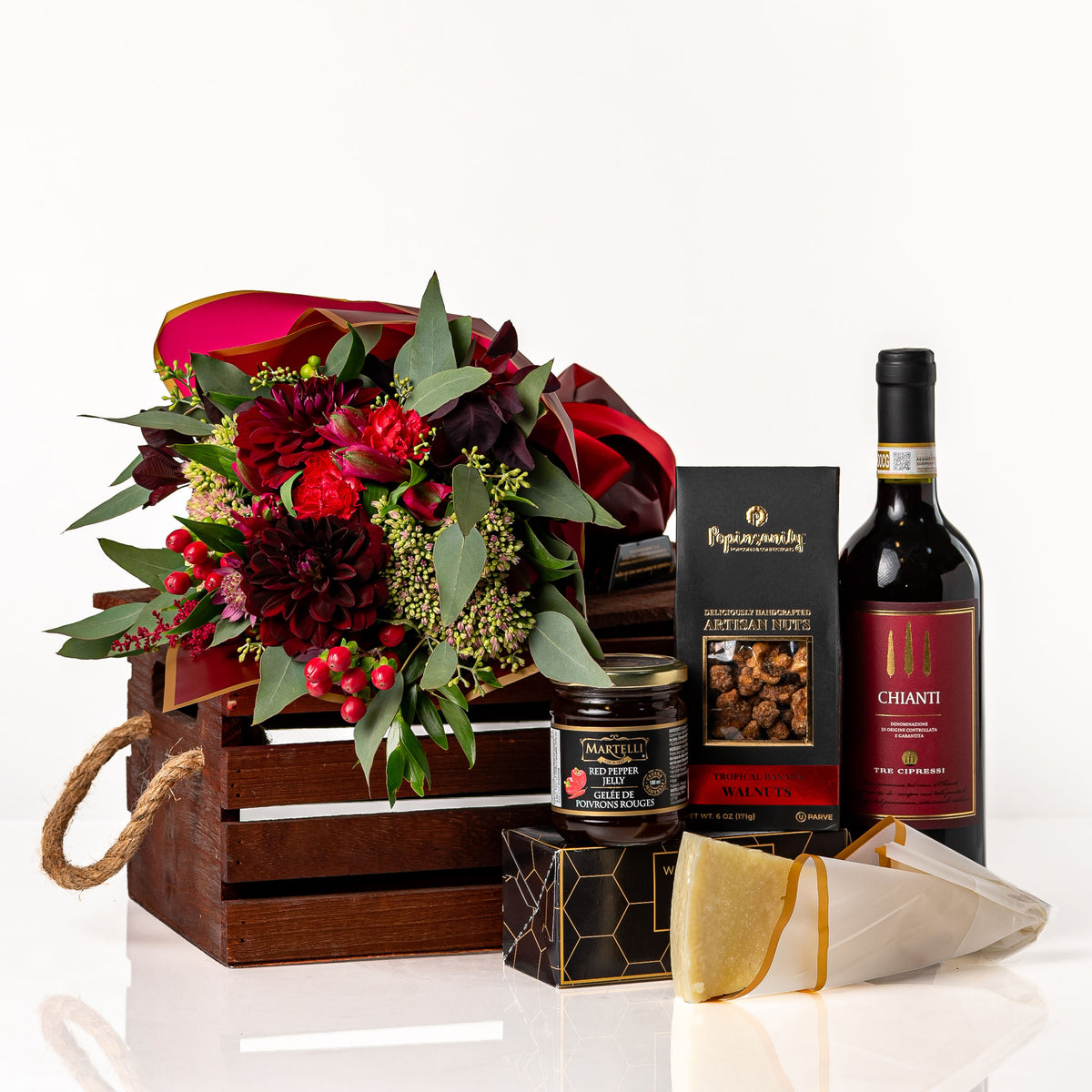 Rouge: a slotted wood crate with rope handles holding a bouquet of burgundy dahlias and red berries, a bottle of Chianti, Martelli red pepper jelly, Popinsanity walnuts, crackers and Parmigiano