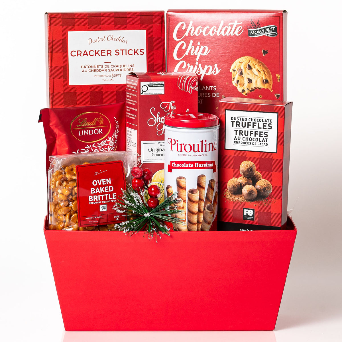 Ruby Red: a red tapered market tray with Lindt Lindor truffles, Pirouline wafer rolls, dusted chocolate truffles, chocolate chip crisps, cheddar cracker sticks and oven baked brittle, with a holiday berry pick