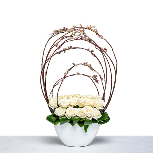 Sculpted Willow arrangement of white roses within a curved willow frame in a white bowl