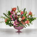 Secret floral arrangement of pink roses, protea and mixed blooms in a lilac footed vase
