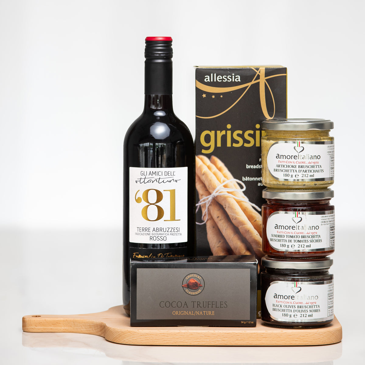 Sip and Dip gift with a bottle of red wine, grissini, preserves and truffles on a wooden board